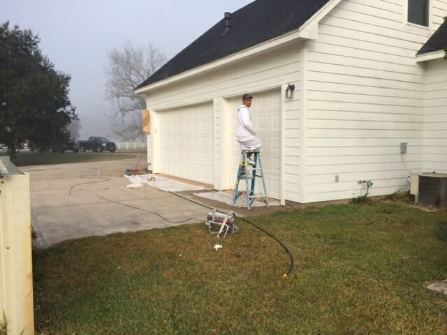 Luxz Painting and Construction Service in Houston Texas image of man painting exterior of a house